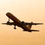 Cargo airplane flying in silhouette against a warm sunset sky.