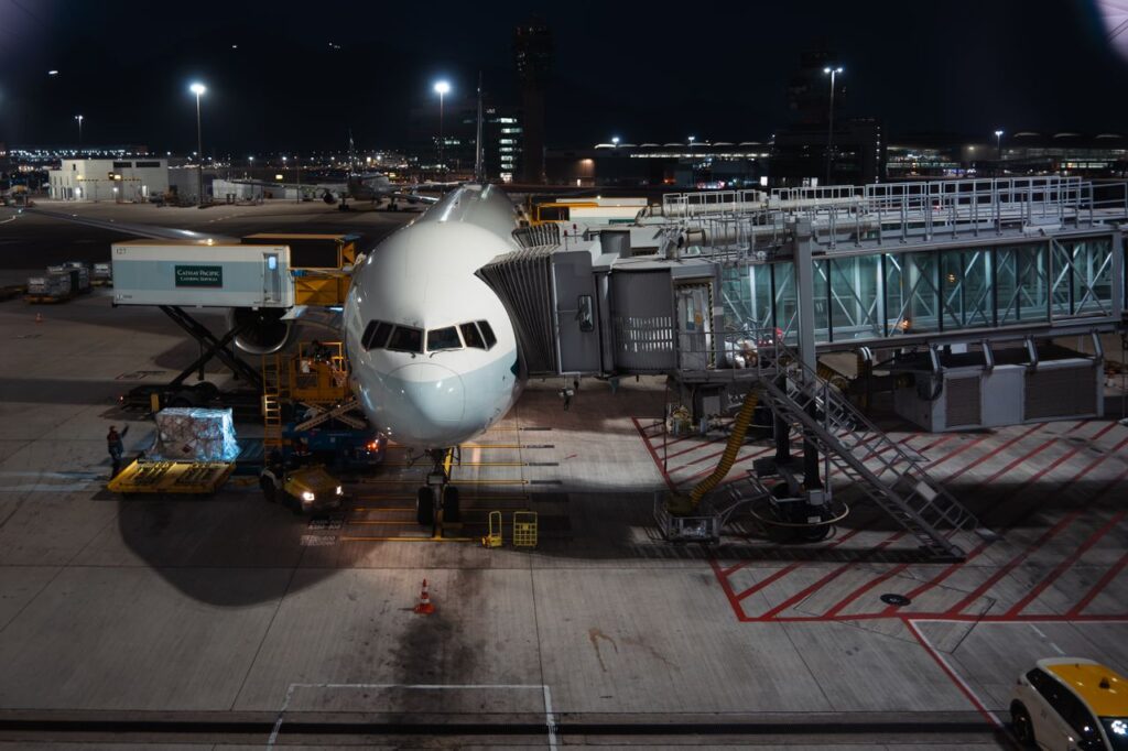 Airplane parked at airport gate during nighttime, unloading cargo and passengers.